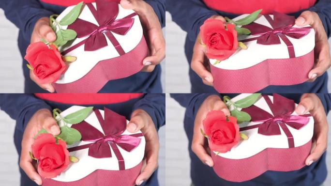 男人的手拿着礼品盒和玫瑰花特写