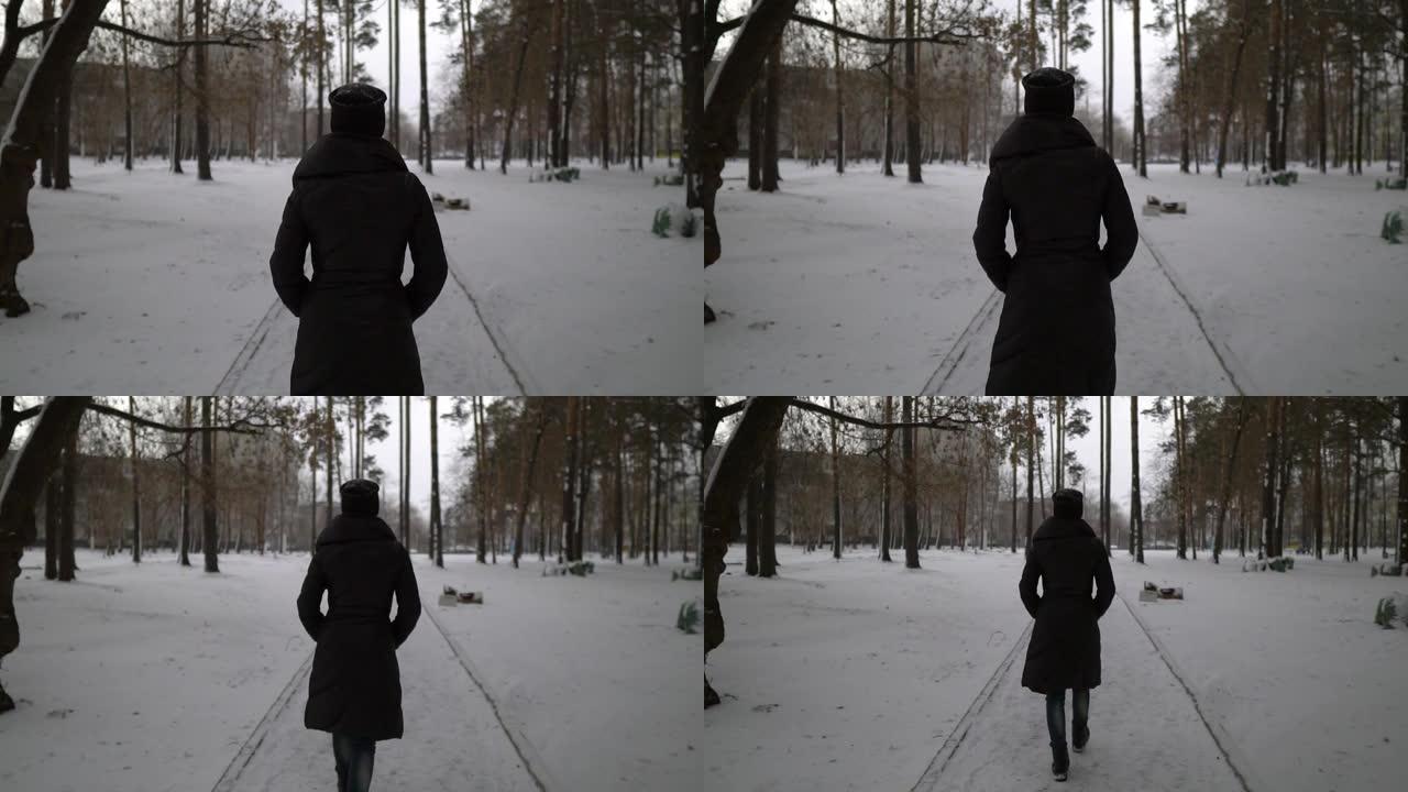 穿着黑色皮大衣的年轻快乐女孩在公园的雪地上吹着。寒假。冬季公园快乐女孩的肖像，她玩雪