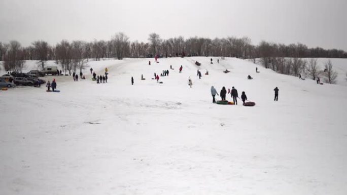 一群人骑在雪地滑梯上。孩子们在充气环上的冰滑梯上列出自己。雪橇、塑料溜冰场