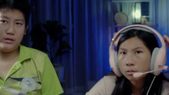 亚洲男孩教他的妹妹用数字平板电脑安装耳机麦克风，然后开始和老师在家上学，在新型冠状病毒肺炎概念期间保