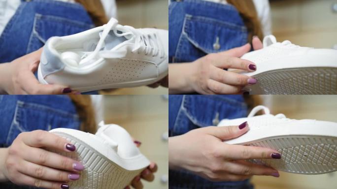 女孩手里拿着一双新的白色运动鞋，检查它们。