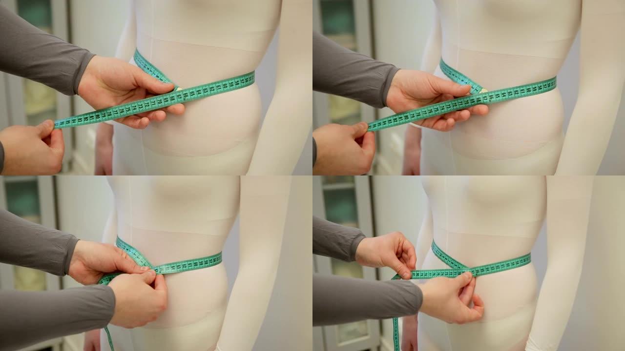 男性的手正在用绿色的绳子测量瘦弱的女孩的腰。没有脸。一个男孩用绿丝带测量他的女孩的腰