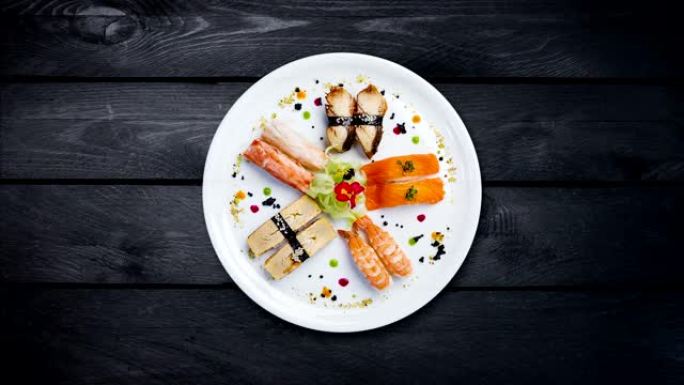 旋转生鱼片放在白色圆形盘子上，装饰有小花，日本食物，俯视图。黑色木质背景