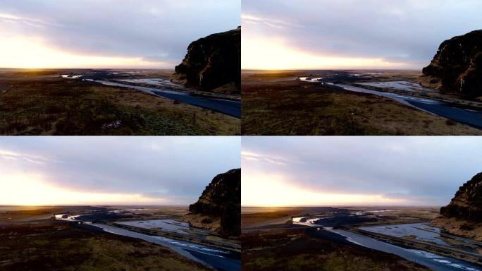 冰岛河流的鸟瞰图。来自瀑布的河流在夕阳下被田野包围。我们可以在背景中看到一座小山。