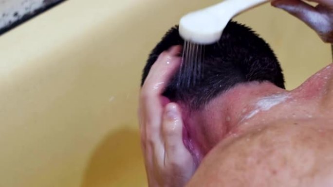 一个年轻人在淋浴下洗他的头