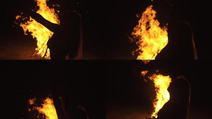 神秘女人的剪影在黑色背景的火飞焰，火花，轮廓轮廓。户外慢动作。高加索人。