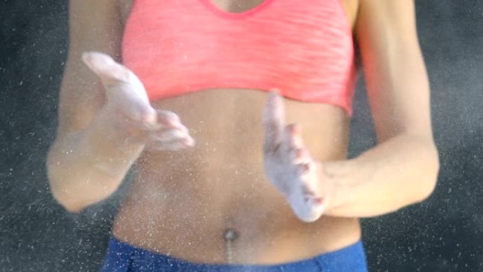 肌肉发达的女人在健身房用滑石粉拍手