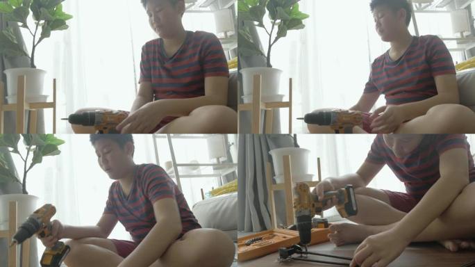 亚洲男孩用螺丝刀修理旧家具或地板上的破桌子，生活方式概念。