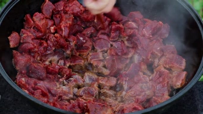 东方菜肴的烹饪过程。红肉在一个大锅里煮沸并在油中炖煮。大型传统亚洲大锅在明火上，称为喀山