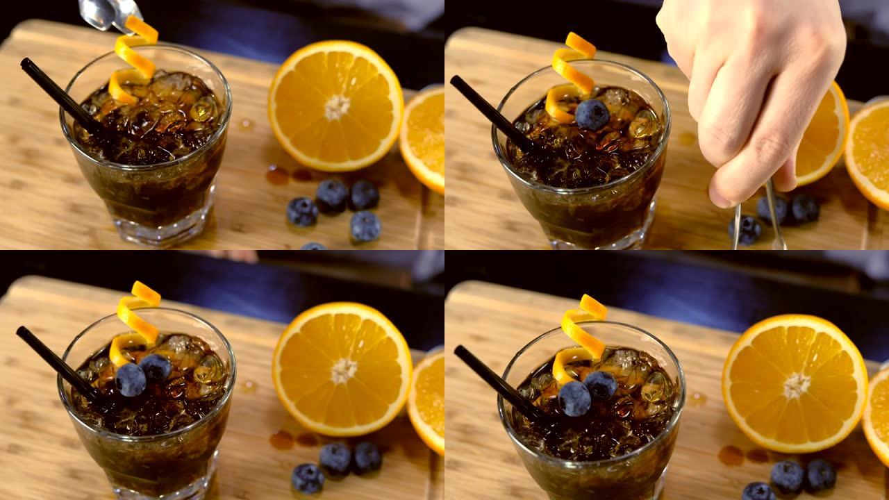 酒保用蓝莓和橙皮在岩石玻璃杯上装饰酒精鸡尾酒。