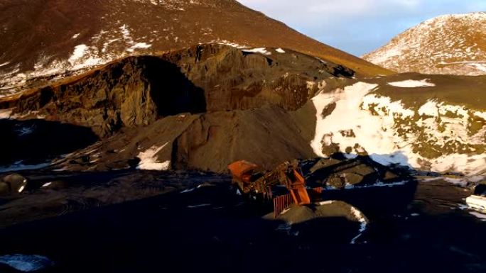 冰岛一个采石场的鸟瞰图覆盖了一点雪。采石场里有卡车在棕色的地面上铲。