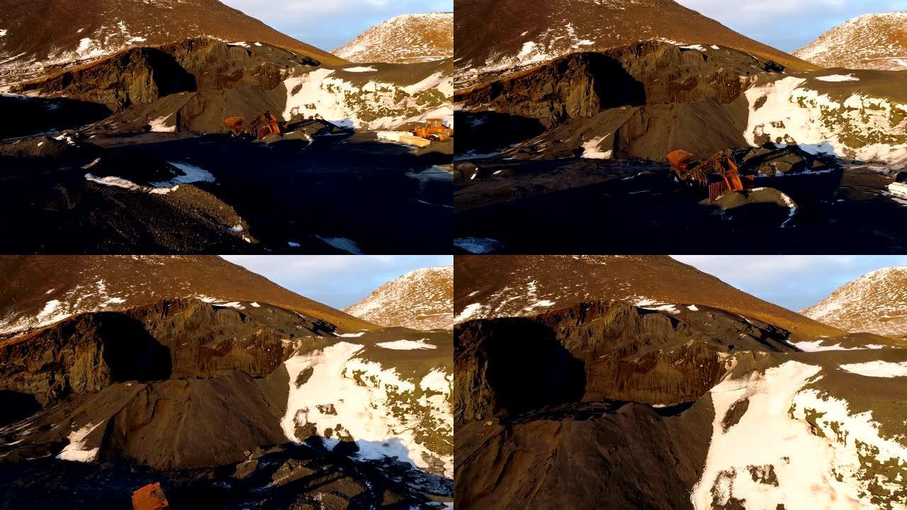 冰岛一个采石场的鸟瞰图覆盖了一点雪。采石场里有卡车在棕色的地面上铲。