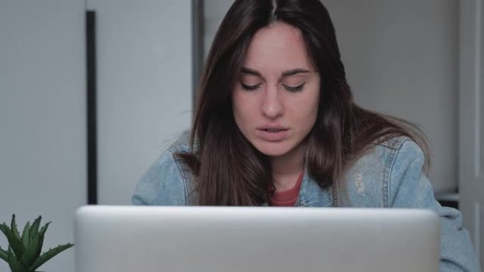 沮丧的女商人在办公室里看着笔记本电脑。沮丧的特写，千禧一代女性思考工作中的错误。悲伤女孩的肖像看屏幕
