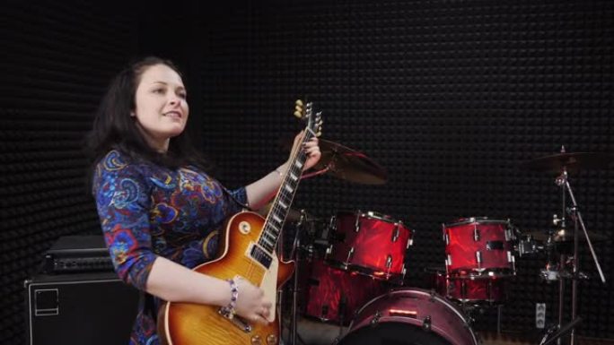 女人在录音棚用电吉他在情感上表演歌曲。女歌手在排练室弹吉他。音乐人在声乐工作室录制歌曲