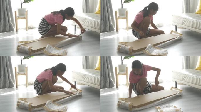 亚洲女孩使用切割器打开棕色盒子，这是从网上购物、生活方式概念中购买的一些家具。