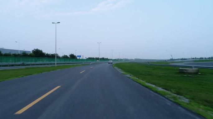 一辆白色汽车在路上行驶 背景是绿色围栏的高速公路 停车场鸟瞰图