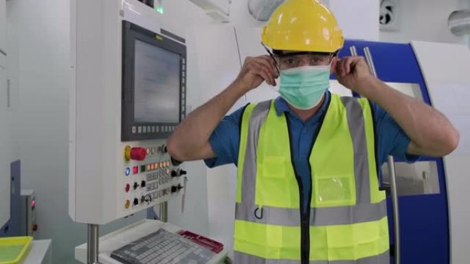 工人/工程师在工作场所或工厂工作前佩戴可保护粉尘烟雾和电晕病毒的处理面罩。然后举起拇指表示自信