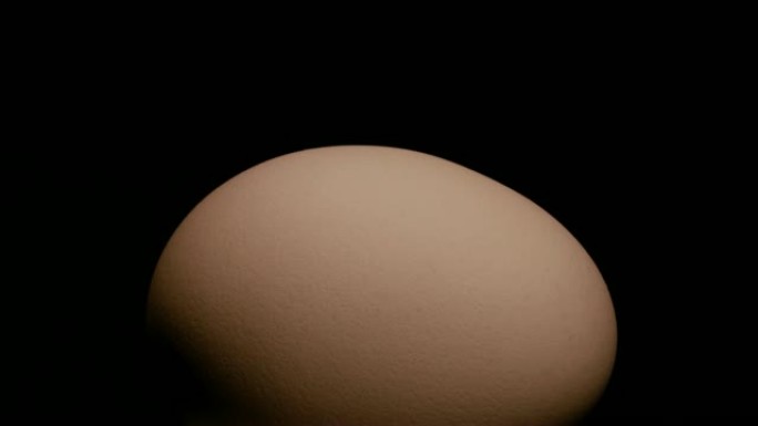 特写，整个半暗度的棕色鸡蛋在黑色背景的转盘上旋转，水平位置