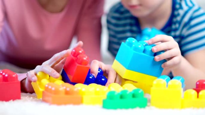 测试过程中，女性儿童心理学家和小男孩玩彩色立方体的特写手