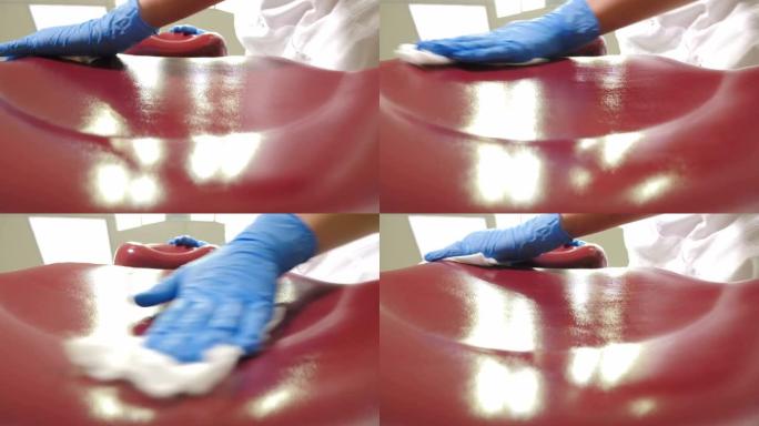 女性牙科助理用消毒液擦拭医疗椅的特写仰视图。清洁消毒医疗牙科单位在现代牙科诊所，经营医疗设施。4 k