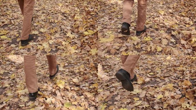 脚在地上行走慢动作视频。秋天的黄色叶子。在城市公园里穿着经典鞋子的男足