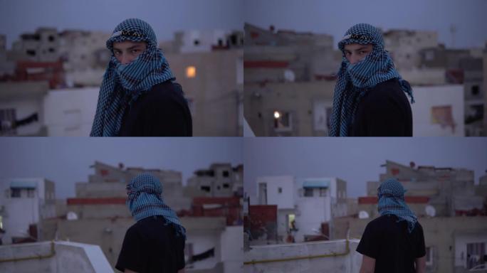 阿拉伯手帕的年轻人。一个男人看着相机走路。在阿拉伯房屋的背景下，在房屋的屋顶上。