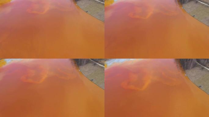 4k航空无人机视图受污染的水与氰化物混合到人工湖中，来自铜矿的橙色有毒残留物淹没了自然环境，生态灾难
