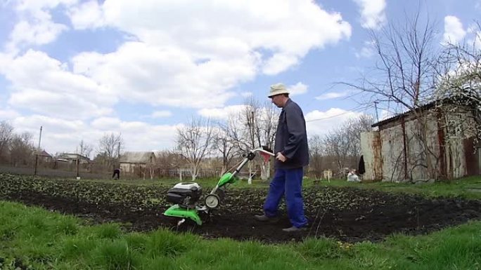 人类用耕作机在花园里耕种土地，为播种准备土壤