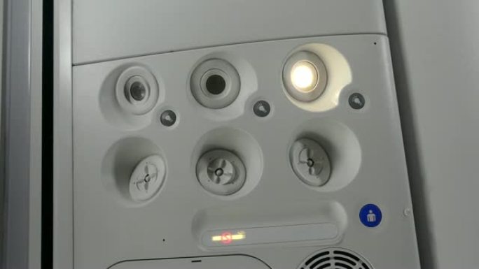 飞机上的乘客打开灯。特写。手动按下飞机上的个人照明按钮。