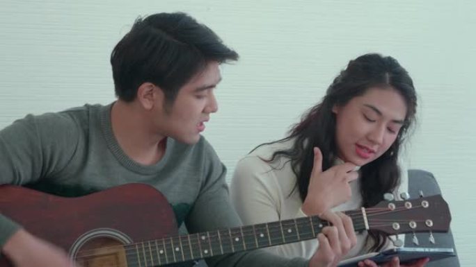 亚洲年轻夫妇一起弹吉他唱歌