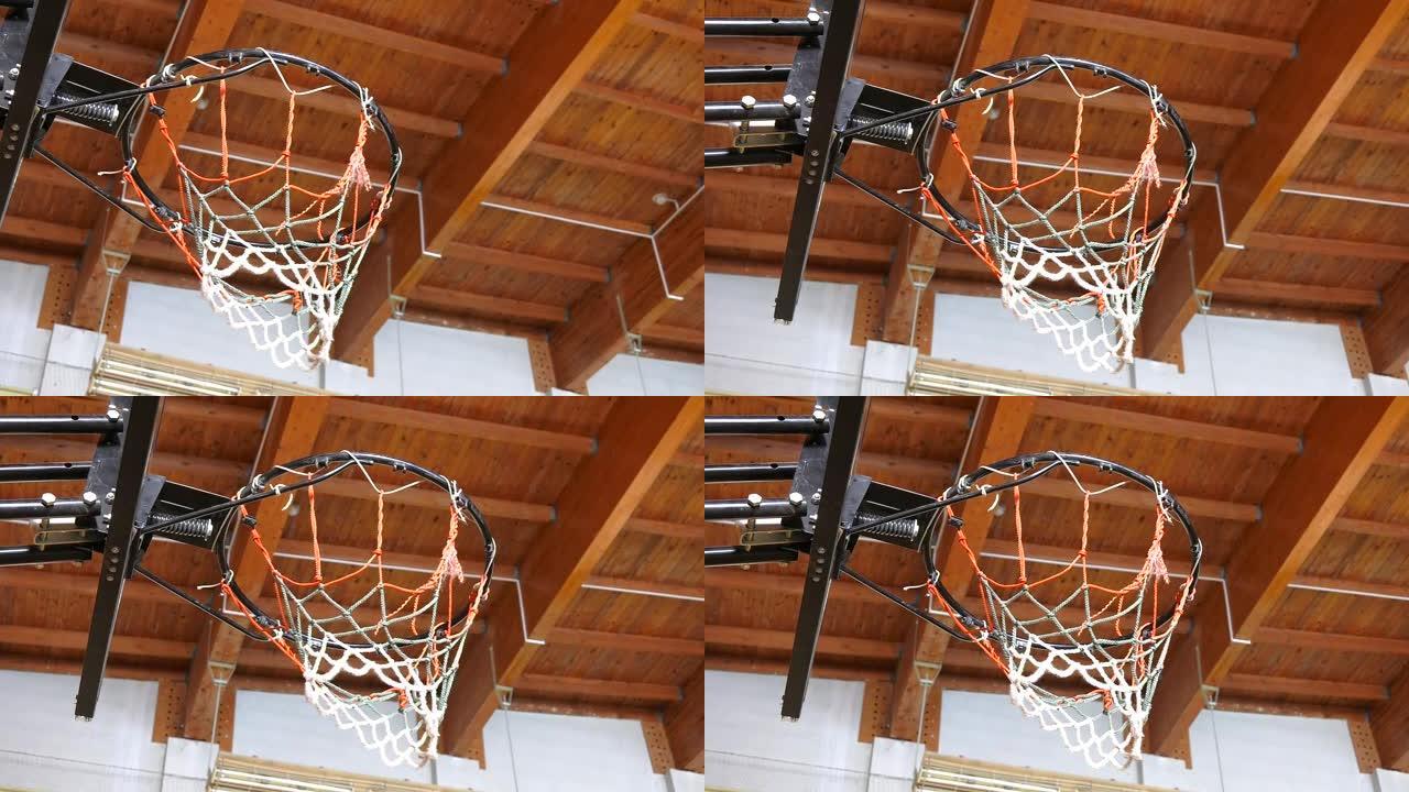 旧学校体育馆的篮球架特写镜头。一个排球被扔进篮球圈。