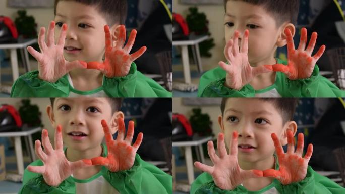 快乐的孩子用橙色水彩展示肮脏的手