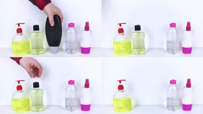 白色背景上的隔离瓶洗涤剂。手拿着一罐洗涤剂。在照片中，洗发水，胶束水，液体肥皂和漱口水。彩色容器中的