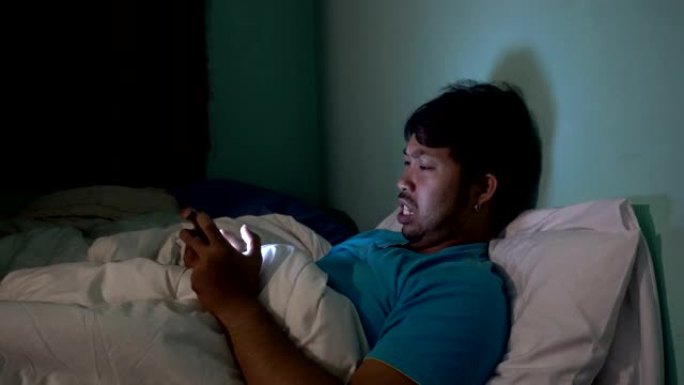 亚洲人晚上在床上玩智能手机