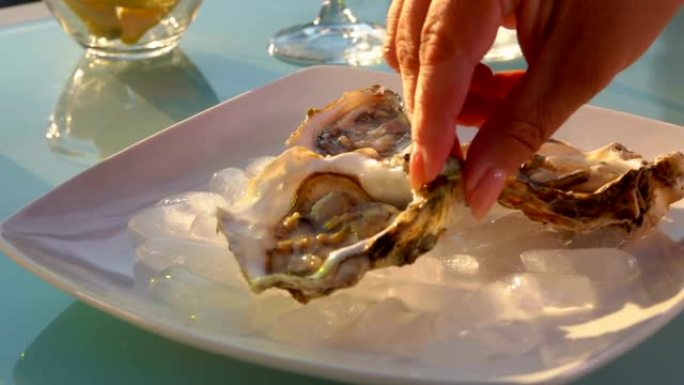 女人的手把开着的牡蛎放在加冰的盘子里。