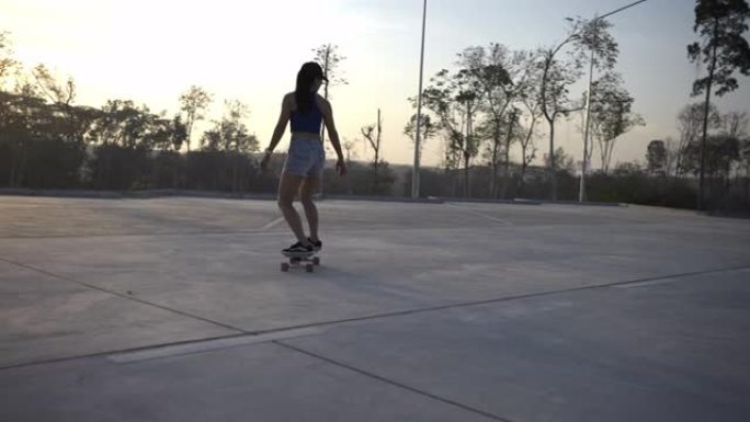在美丽的夏日，亚洲女性在户外冲浪溜冰鞋或溜冰鞋。快乐的年轻女性早上在公园玩冲浪滑板。