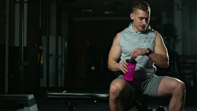 健身肌肉发达的男性在健身房喝水，保持水分充足
