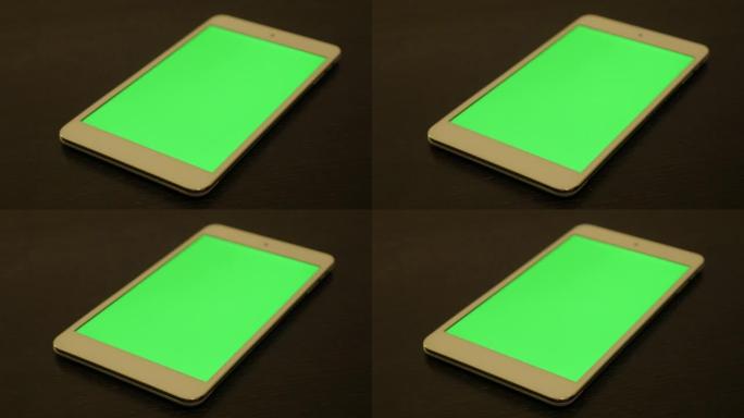 深色木质表面慢速盘4K上的绿屏平板显示器