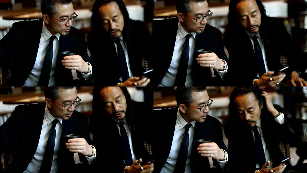 两名在咖啡馆使用智能手机的现代商人