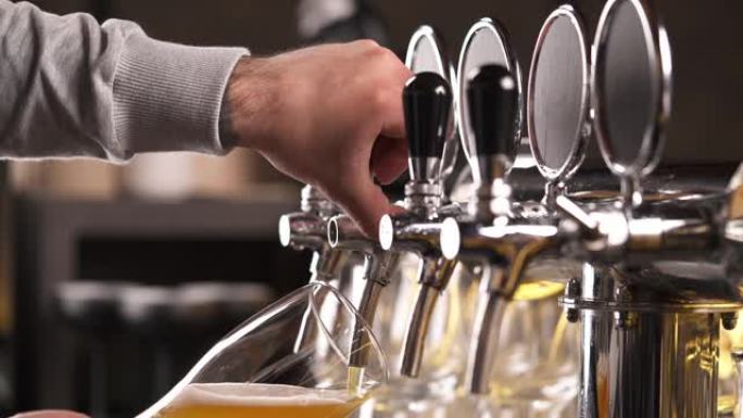 酒保用水龙头倒啤酒的手。装满啤酒的玻璃的特写演示