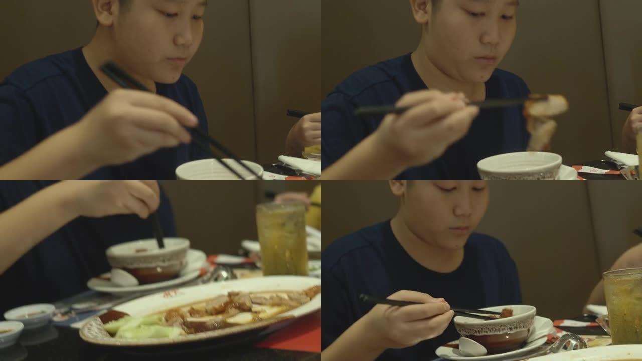 亚洲男孩在家庭，生活方式概念的餐厅里吃寿喜烧，sha锅或火锅。