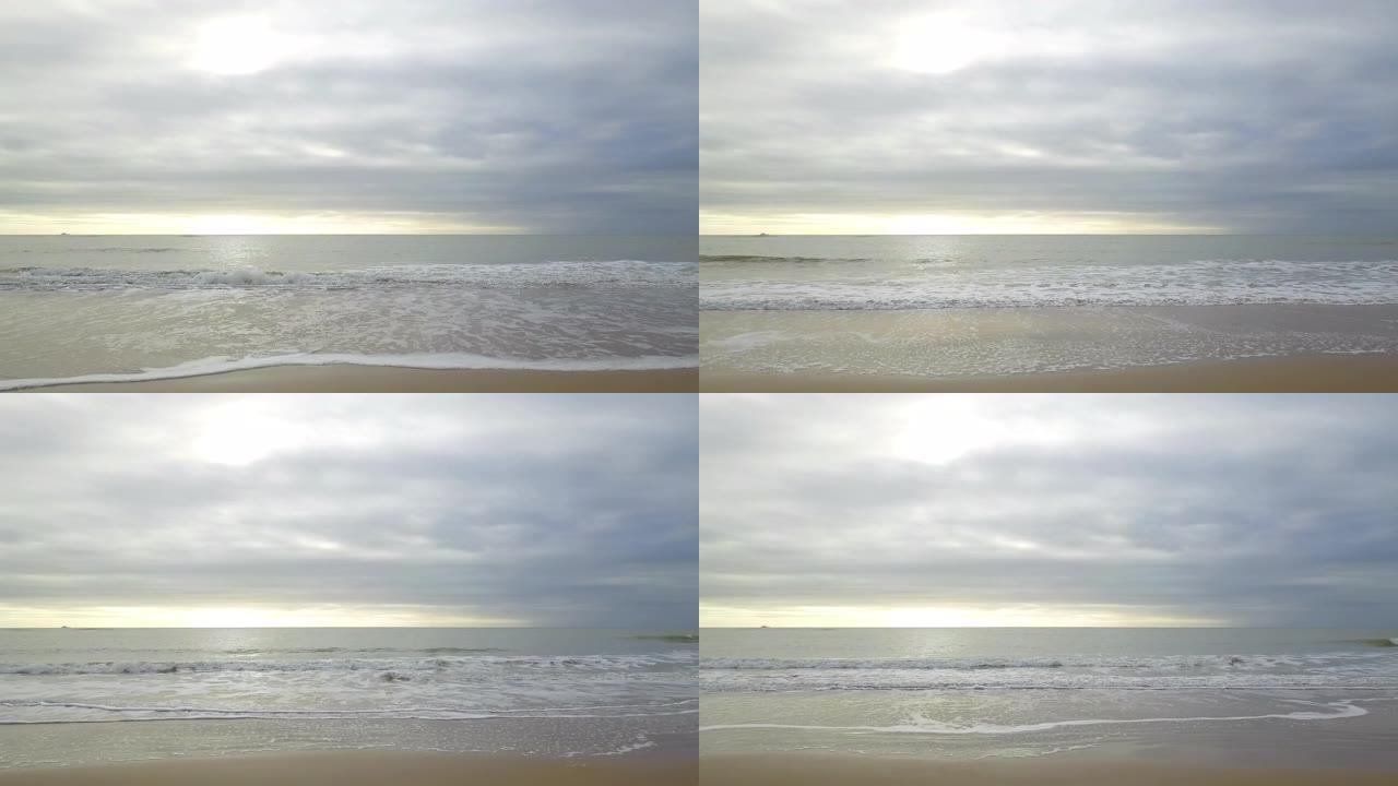 飞掠海滩的鸟瞰图，海浪逼近，日落时白色喷雾