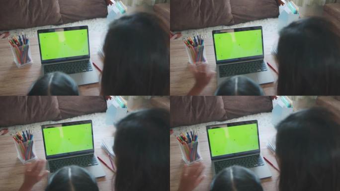 亚洲母女在家绿屏笔记本电脑上的视频通话在线向朋友问好。由于Covid 19大流行，孩子在家上学，父母