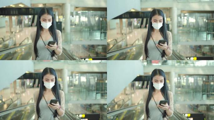 亚洲妇女在机场使用手机，戴医用口罩。