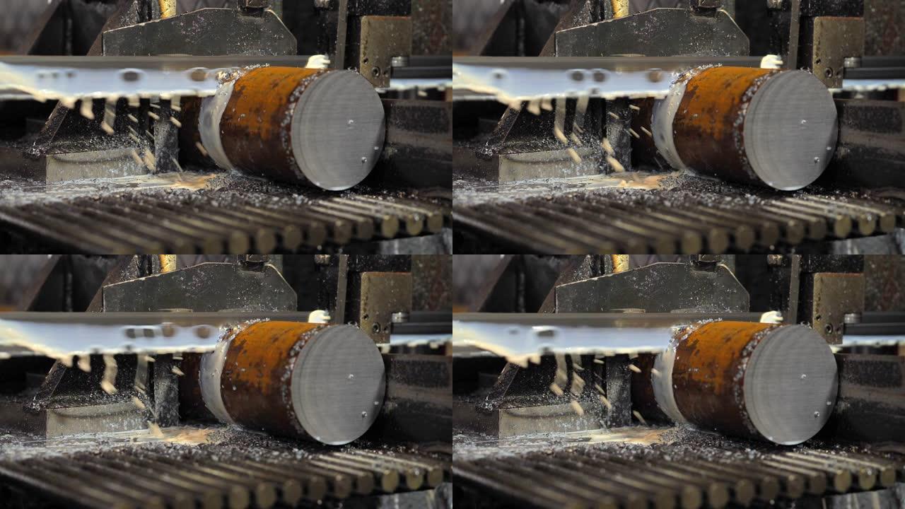 用冷却液切割钢棒的工业机器。用冷却剂切割原始金属的带锯。
