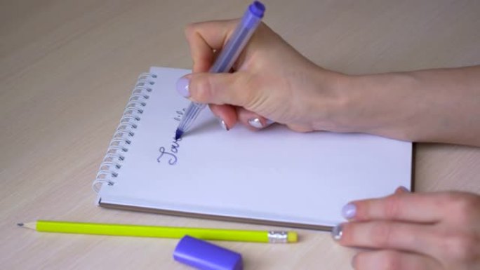 女孩在一张记事本上用蓝色记号笔写下题词 “爱就是生命”