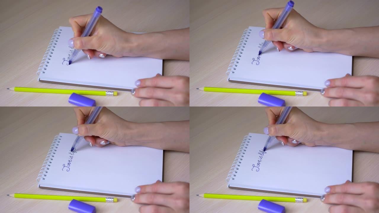 女孩在一张记事本上用蓝色记号笔写下题词 “爱就是生命”