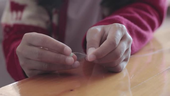 亚洲儿童女孩的近手相在家里有意将珠子穿在一根绳子上。孩子创造手工手镯来发展手的活力。