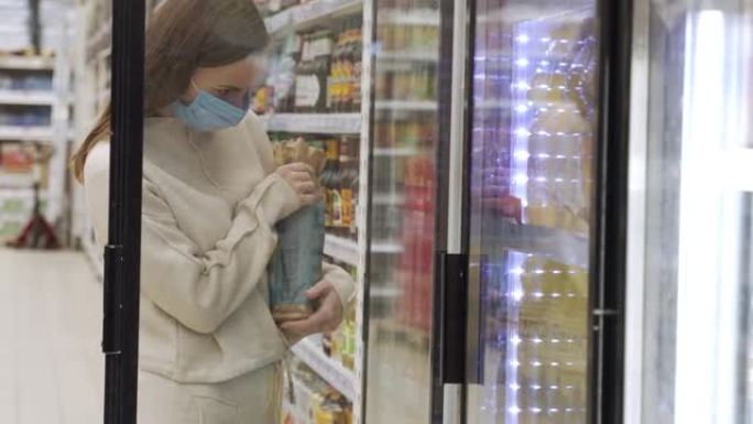 戴着医用口罩的女人在杂货店选择啤酒