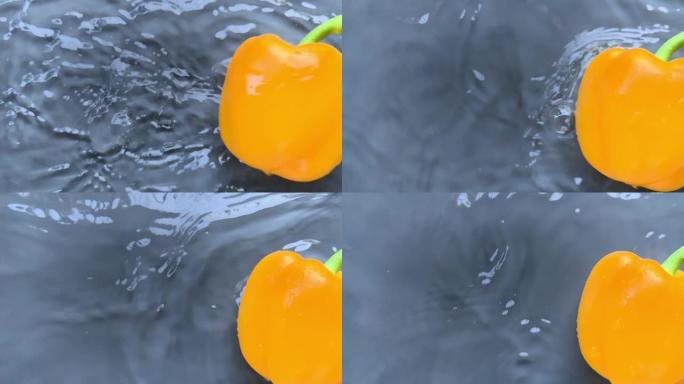 黄椒在水中飞溅的慢动作中掉入水中